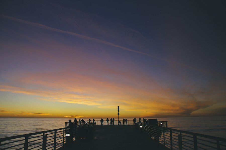 People gathered at the end of a jetty over the water at dusk
